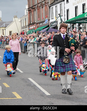 Young Man Playing Bagpipes menant une course de brouettes pour enfants, Moffat, Dumfries & Galloway, Scotland, UK Banque D'Images