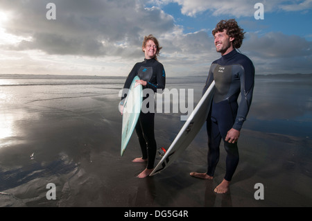 Couple standing on beach with surfboards, on a une caméra Gopro surf attaché à Banque D'Images