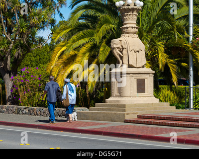 Vieux couple walking dog passé elephant monument sur Bridgeway à Sausalito, Californie Banque D'Images