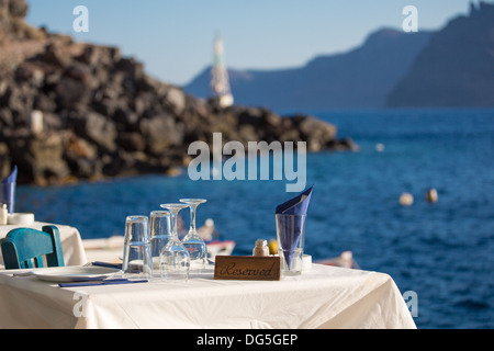 Table réservée en face de la mer Égée, dans l'arrière-plan flou , vous voyez le littoral de Santorin. Banque D'Images