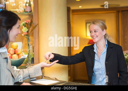 Jeune femme à la réception de l'hôtel Banque D'Images