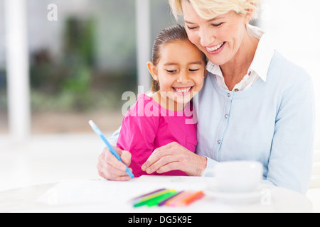 Happy grandmother enseigner sa petite-fille comment dessiner à la maison Banque D'Images