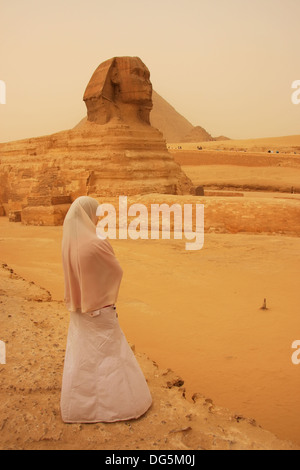 Femme musulmane en robe blanche debout près du Sphinx, Le Caire, Egypte Banque D'Images