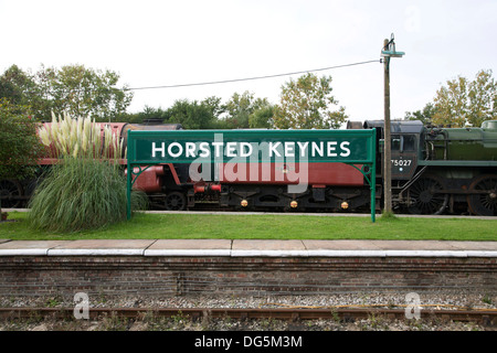 L'Horsted Keynes Bluebell Railway signe avec la plate-forme des locomotives à vapeur garées derrière. Banque D'Images