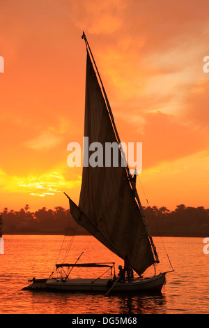 Bateau naviguant de felouque sur le Nil au coucher du soleil, Luxor, Egypte Banque D'Images