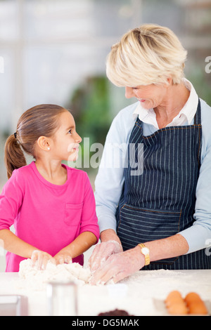 Adorable petite fille aider sa grand-mère baking in kitchen Banque D'Images