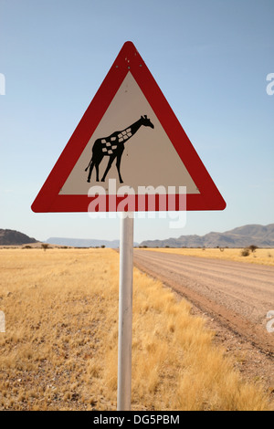 Danger Girafe Crossing Road Sign près de route de campagne, la Namibie, l'Afrique de l'Ouest Banque D'Images