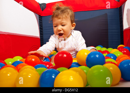 Heureux bébé jouant avec des boules dans un parc pour enfants Banque D'Images