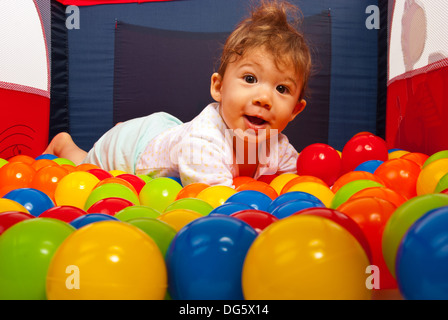 Surpris happy baby laying on boules colorées dans playpan Banque D'Images