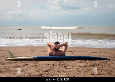 Mar del Plata, Buenos Aires, Argentine. 15 Oct, 2013. Un homme se penche sur son surf se détend comme sur la plage. Le printemps a commencé dans l'hémisphère sud et les surfeurs et les familles sont à apprécier le soleil et le temps chaud. © Ryan Noble/ZUMAPRESS.com/Alamy Live News Banque D'Images
