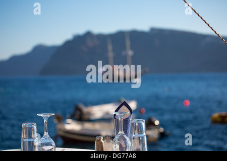 Table réservée en face de la mer Égée, dans l'arrière-plan flou , vous voyez le littoral de Santorin. Banque D'Images