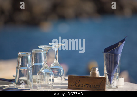 Table réservée en face de la mer Égée, dans l'arrière-plan flou , vous voyez le littoral de Santorin. Banque D'Images