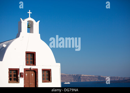 Une petite église surplombant la caldera à Oia, Santorini.Dans la distance que vous voyez un blanc navire de croisière. Banque D'Images