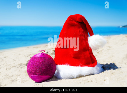 Chapeau de Noël avec boule de noël sur la plage à l'océan - vacances concept Banque D'Images