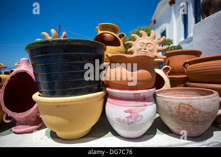 Divers pots de céramique et autres objets à vendre au marché local, à l'arrière-plan les maisons blanches et bleues typiques de la Grèce Banque D'Images