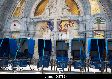 Prêts de fauteuils roulants bleu en face de l'église dans le sanctuaire de Lourdes, 2013. Tous les fauteuils roulants a été un don d'un rendez-vous Banque D'Images