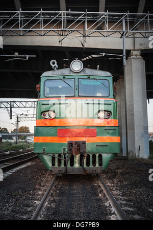 Locomotive verte avec des bandes rouges sur la cabine se tient sous le pont sur le chemin de fer Banque D'Images