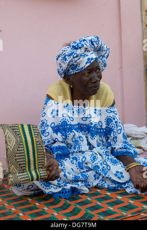 Sénégal, Saint Louis. Vieille Femme Sénégalaise avec ventilateur assise sur son porche. Banque D'Images