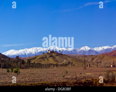 Mosquée sur colline dans désert avec altas enneigés des montagnes en arrière-plan Banque D'Images