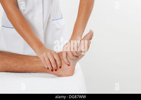 Jeune femme ostéopathe manipule et masser le pied d'un jeune homme ou à la cheville muscles en appliquant une pression avec les mains Banque D'Images