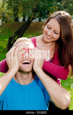 Jeune fille couvrant ses petits amis les yeux pour lui faire une surprise Banque D'Images