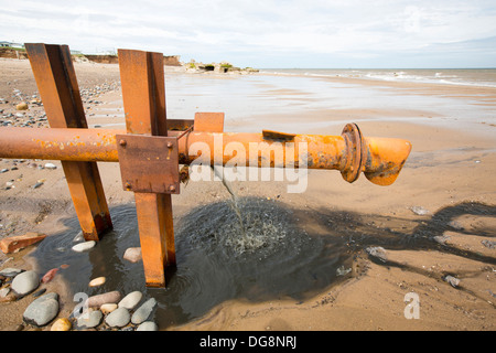 La vidange des eaux usées brutes directement sur la plage à partir d'un tuyau d'eaux usées provenant d'un caravan park à Kilnsea, rejette Point, Yorkshire, UK. Banque D'Images