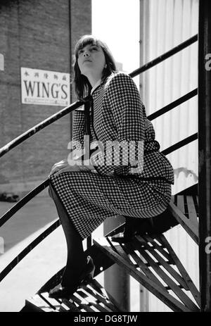 B&W shot mode montrant une jeune femme assise dans un escalier en spirale. Banque D'Images