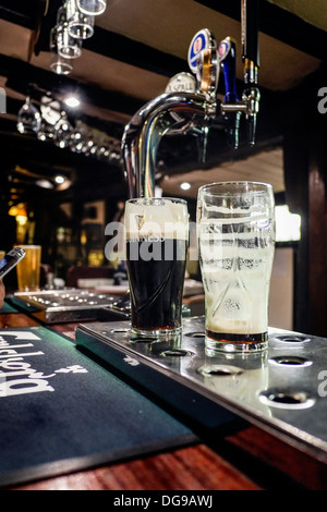 Pinte de Guinness lunettes sur le bar d'un pub. Banque D'Images