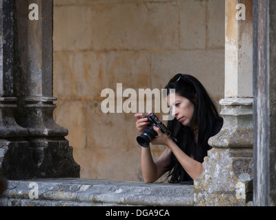 Jeune femme à la recherche de l'écran LCD à l'arrière de son appareil photo numérique tout en prenant des photos Banque D'Images