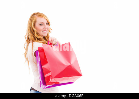 Jeune rousse woman with shopping bags tournant autour de sur fond blanc Banque D'Images