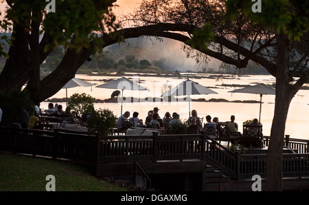 Invités sur le coucher du soleil terrasse en admirant le coucher du soleil sur le fleuve Zambèze et à l'hippopotame, le Royal Livingstone Hotel, Afrique Zambie Banque D'Images