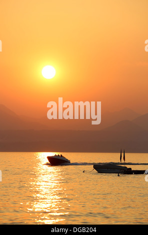 Coucher de soleil sur le lac de Garde à Desenzano del Garda en Italie avec un hors-bord dans la photographie. Banque D'Images