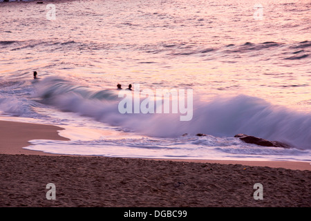 Les surfeurs sur la plage de Porthmeor à St Ives, Cornwall, UK, au coucher du soleil. Banque D'Images