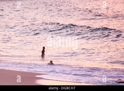 Les surfeurs sur la plage de Porthmeor à St Ives, Cornwall, UK, au coucher du soleil. Banque D'Images