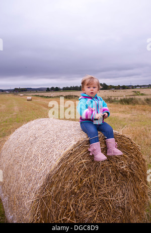 Baby sitting sur botte à la recherche à l'appareil photo Banque D'Images