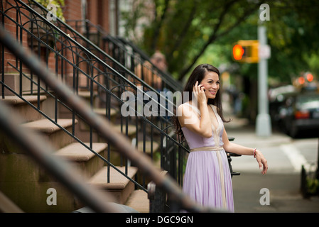 Mid adult women using mobile phone par brownstone bâtiments dans Greenwich, New York Banque D'Images