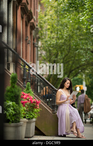 Woman using digital tablet par brownstone bâtiments dans Greenwich, New York Banque D'Images