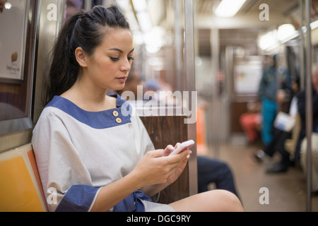 Woman using mobile phone on subway, New York Banque D'Images