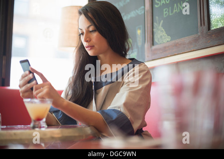 Mid adult women using mobile phone in restaurant Banque D'Images