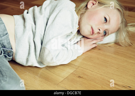 Jeune fille allongée sur un plancher de bois, à l'écart Banque D'Images