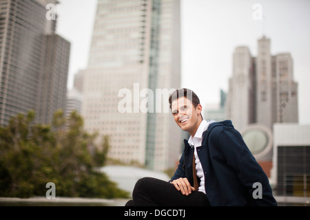 Young man sitting and smiling in city Banque D'Images