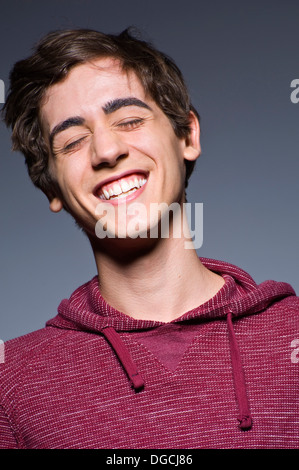 Jeune homme rire avec les yeux clos, studio shot Banque D'Images