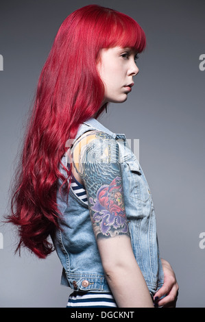 Jeune femme aux longs cheveux rouges et des tatouages, profile Banque D'Images