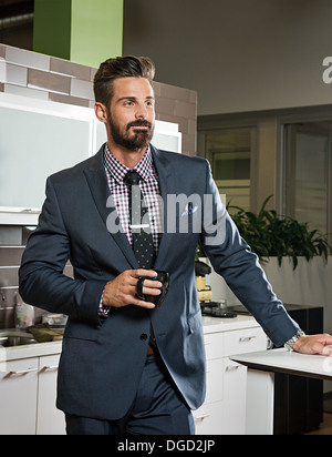 Young businessman holding cup in office cuisine Banque D'Images