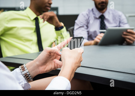 Young businesswoman looking at smartphone in meeting Banque D'Images