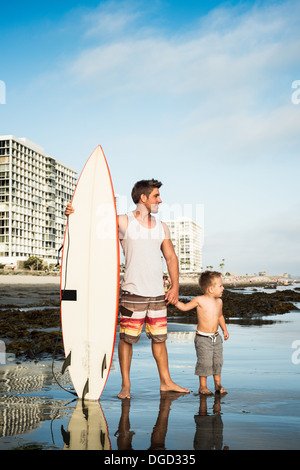 Jeune homme tenant une planche de surf avec des fils en mer Banque D'Images