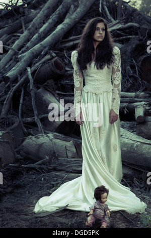 Femme en robe de mariage avec couper des arbres et creepy doll Banque D'Images