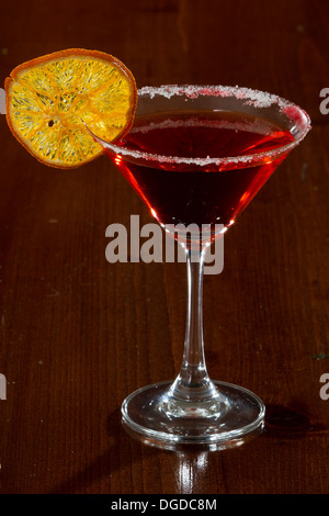 Maison de vacances martini servi sur une barre sombre avec une roue d'orange garnir Banque D'Images