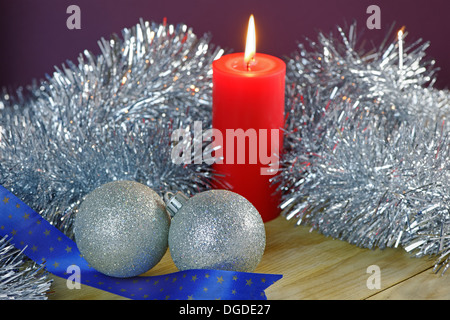 Boules de Noël, guirlandes et bougies sur un premier plan texturé en bois Banque D'Images