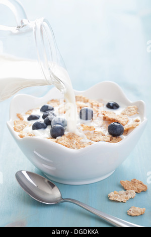 Verser le lait sur les flocons de bleuets Banque D'Images